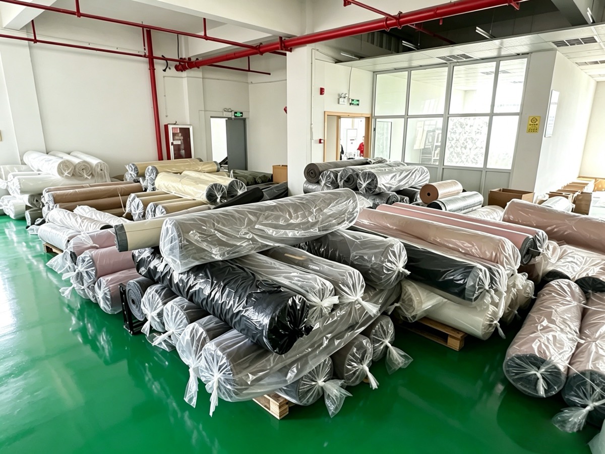 Material stock at the Pujiang factory — palletized fabric and mesh rolls ready for production