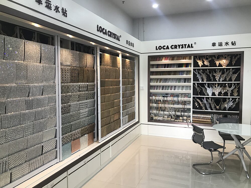 LOCACRYSTAL Yiwu showroom — full sample wall of rhinestone trims, mesh, lace and bangle stickers under the LOCA CRYSTAL brand display